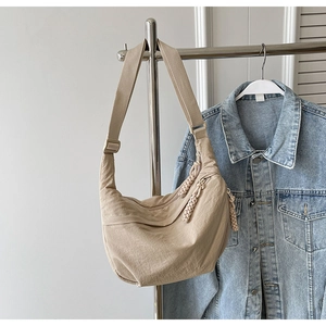 Détail du sac croissant en nylon beige avec tirette tressée et bandoulière réglable
