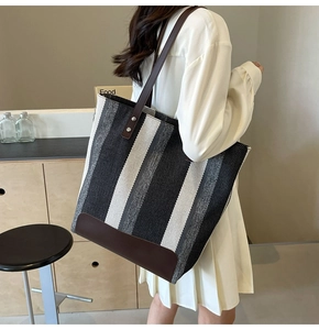 Detailed side view of large canvas tote bag with striped pattern and leather handles