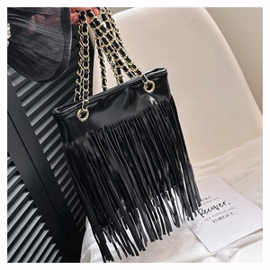 Détail du sac cabas en cuir noir avec longues franges et bandoulière en chaîne dorée