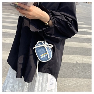 Detalle del mini bolso denim con lazo de cuero blanco y etiqueta de logo de arcoíris