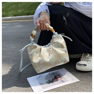 Détail du sac en soie à motif paysage avec poignée en perles d'ambre et cordon