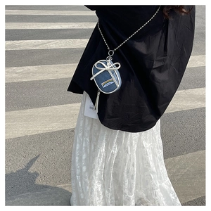 Primer plano de mini bolso vaquero azul con lazo blanco y correa de cadena plata
