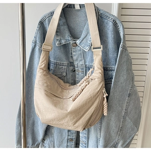 Détail du sac bandoulière demi-lune en nylon beige avec nœuds tissés sur le zip