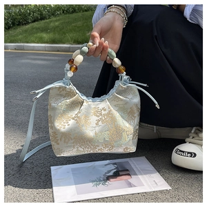 Détail du sac jacquard de style chinois avec motifs dorés et poignée en perles colorées