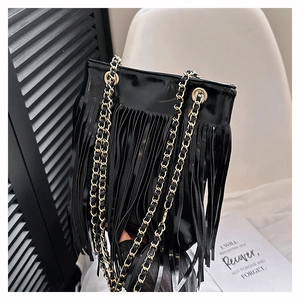 Gros plan du sac seau à franges en cuir noir brillant avec bandoulière en chaîne