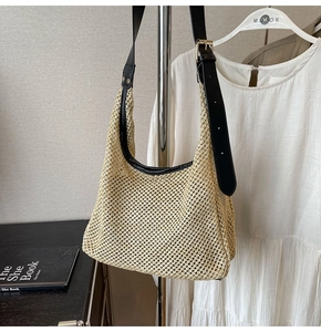 Detail of hand-woven straw bag with black leather shoulder strap and golden buckle