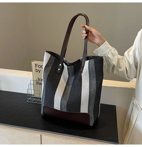 Close-up of the striped canvas tote with dark brown leather handles and rivet accents
