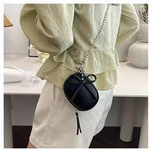 Detalle del mini bolso bandolera de cuero negro con lazo decorativo y cadena de bolas plateada