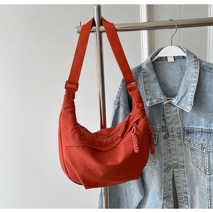 Détail du sac bandoulière en nylon orange vif avec bandoulière réglable et zip tressé