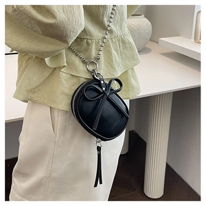 Primer plano del mini bolso redondo negro con detalle de lazo y cadena de bolas plateada