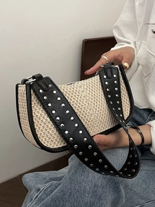 Sac croissant tissé avec bordure en cuir noir et rivets argentés porté par un mannequin