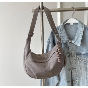 Détail du sac croissant en nylon taupe avec bandoulière réglable et tirette tressée