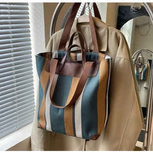 Detail of canvas tote bag with contrast stripes and leather reinforced bottom corners