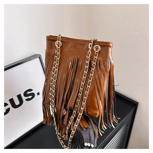 Gros plan du sac seau marron à franges avec longues franges et chaîne dorée