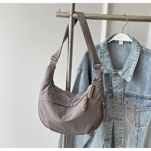 Détail du sac demi-lune en nylon gris-violet avec fermeture éclair et bandoulière