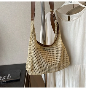 Detail of woven straw shoulder bag with dark leather strap and metal buckle detail