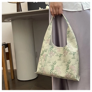 Detailed close-up of light green oriental bag with vintage floral embroidery and stitching