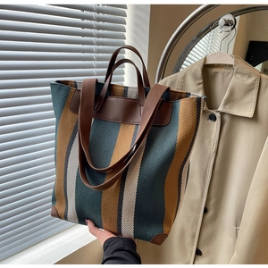 Detail of striped woven tote bag featuring leather handles and vintage texture in soft light