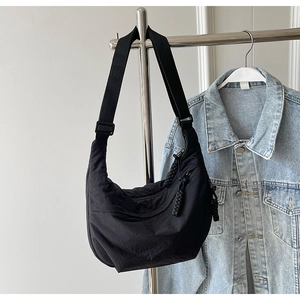 Détail du sac croissant en nylon noir avec bandoulière réglable et tirette tressée