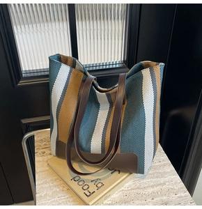 Close-up of contrast striped canvas texture and premium dark brown leather handles