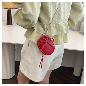 Detalle del bolso mini de cuero rojo con lazo decorativo y cadena de bolas de plata
