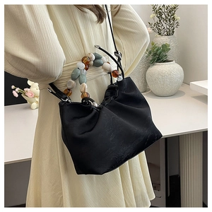 Détail du sac bandoulière noir froncé avec poignée en perles colorées et finition satinée