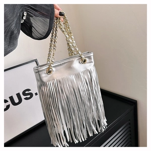 Détail d'un sac cabas argenté avec de longues franges et des poignées en chaîne dorée