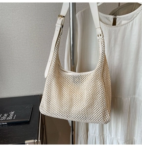 Detail of hand-woven cream hobo bag with adjustable white leather strap and gold buckle