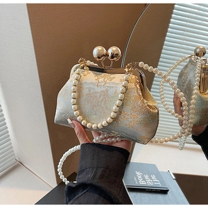 Close-up of vintage golden brocade purse with metal frame and elegant pearl strap