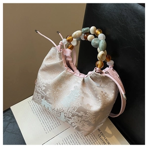 Détail du sac seau chinois rose avec motif jacquard de paysage et poignée en perles