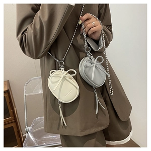 Vista detallada de mini bolsos bandolera ovales con lazo y cremalleras de flecos largos