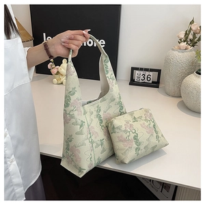 Detail of floral jacquard tote bag set featuring matching mini zippered pouch on a table