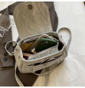 Dettaglio della borsa a tracolla plissettata grigio chiaro che mostra lo spazio interno