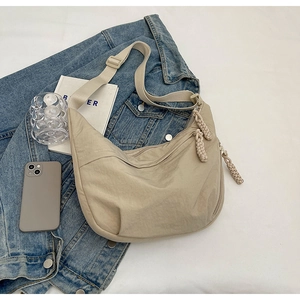 Détail d'un sac demi-lune beige en nylon avec tirettes tressées et bandoulière réglable
