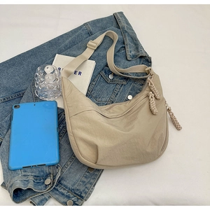 Détail du sac demi-lune en nylon beige montrant les plis et la bandoulière réglable en vue