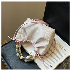 Détail d'un sac à main en jacquard fleuri avec poignée en perles sur un livre