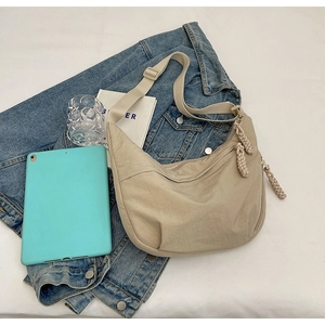 Sac bandoulière beige en nylon sur veste en jean avec tablette pour illustrer la capacité