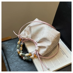 Détail du tissu jacquard rose et de la poignée en perles colorées du sac à main élégant