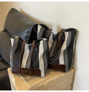 Detail of striped canvas tote bags with premium brown leather handles on stone surface