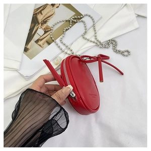 Detalle de mini bolso bandolera de cuero rojo con cadena plateada y un lazo