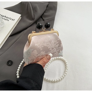 Detail of pink embroidery bag with golden frame, pearl chain and black ball clasp closure