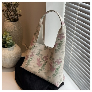 Close-up of floral embroidery on a beige canvas bucket bag near a window sill