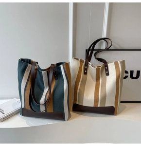Detail of striped canvas tote bags featuring premium leather trim and sturdy handles