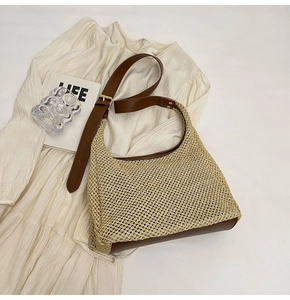 Detail of woven straw hobo bag featuring brown leather trim and golden metal buckle