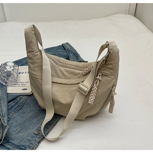 Gros plan détaillé du sac bandoulière en nylon beige avec sangle réglable et texture