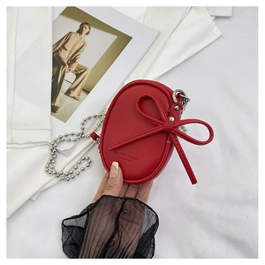 Detalle de mini bolso de cuero rojo con lazo grande y correa de cadena plateada