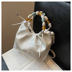 Détail de la poignée en perles et de l'imprimé floral sur sac à main blanc à cordon