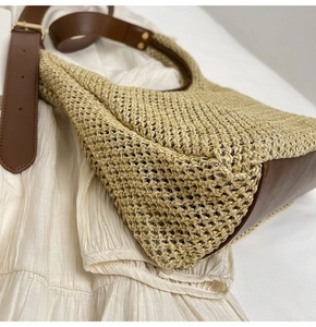 Detail view of woven straw bag texture with premium brown leather base and reinforced stitching
