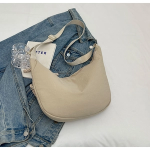 Vue de dessus du sac croissant en nylon beige avec bandoulière et accessoires