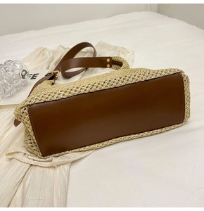 Detail showing high-quality straw weave texture and sturdy brown leather bottom on beach bag